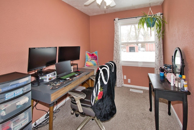 carpeted office space featuring visible vents, a textured wall, baseboards, and ceiling fan