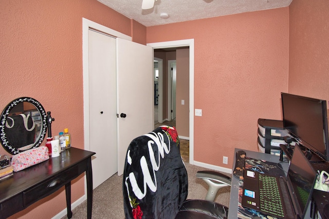 office featuring ceiling fan, a textured ceiling, carpet flooring, and a textured wall