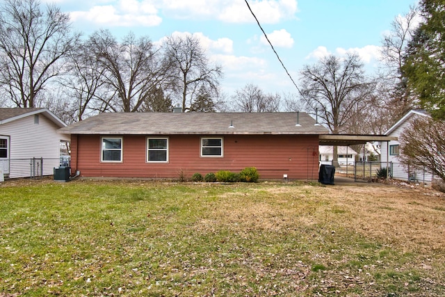 rear view of property with central air condition unit, an attached carport, and a lawn