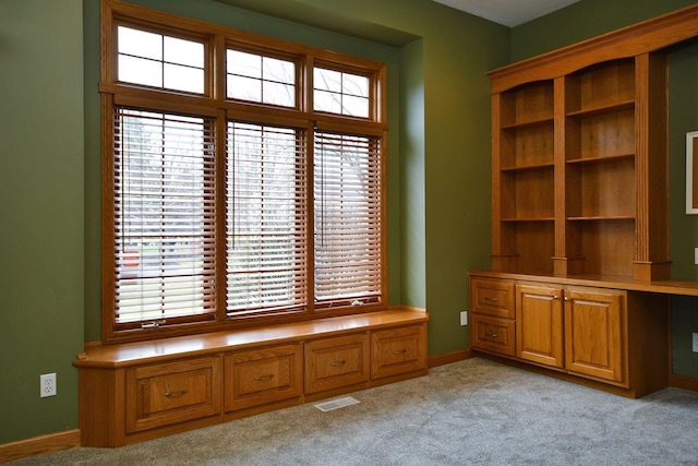 unfurnished room featuring a healthy amount of sunlight, light carpet, and visible vents