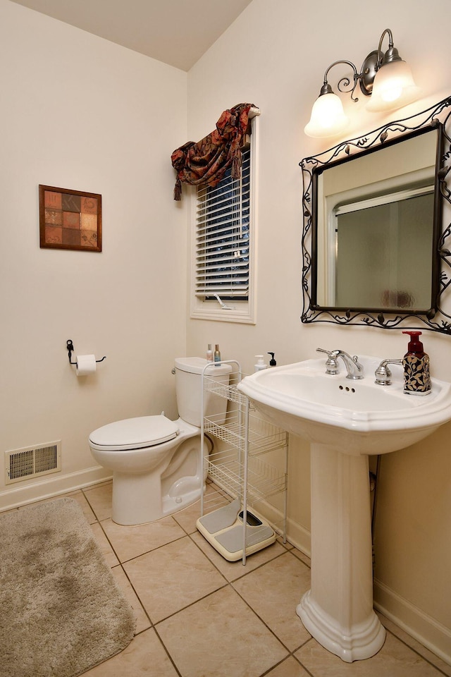 half bathroom featuring toilet, baseboards, visible vents, and tile patterned floors