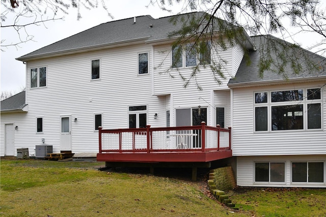 rear view of property featuring central AC, a yard, a deck, and roof with shingles