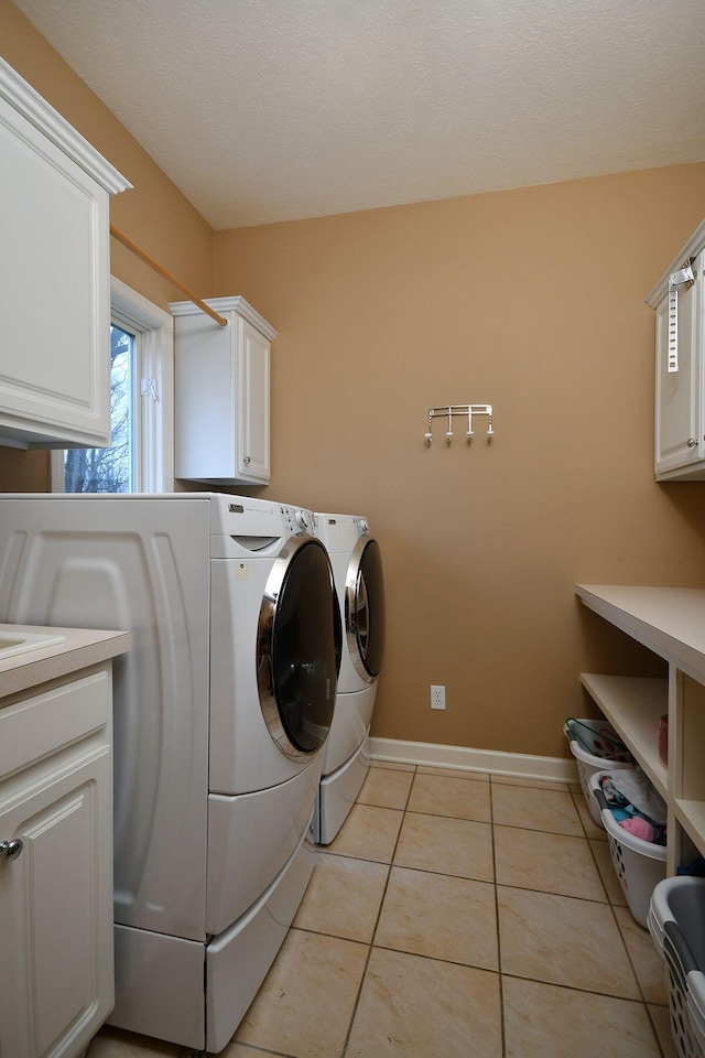 clothes washing area featuring cabinet space, light tile patterned floors, baseboards, and independent washer and dryer