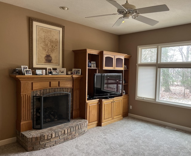 living area featuring a ceiling fan, light carpet, a fireplace, and baseboards