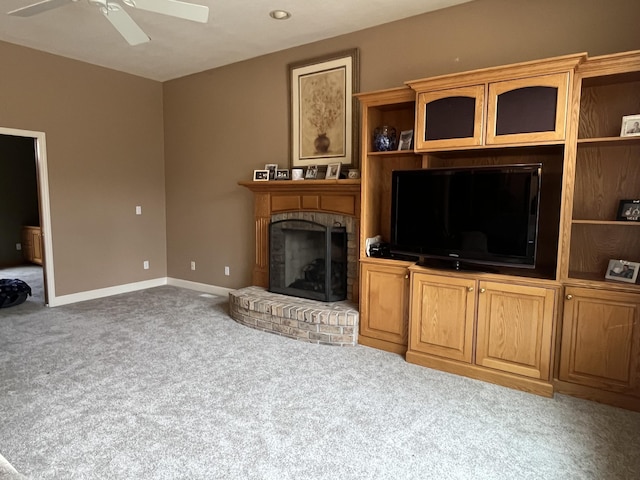 living area featuring carpet floors, a brick fireplace, baseboards, and a ceiling fan