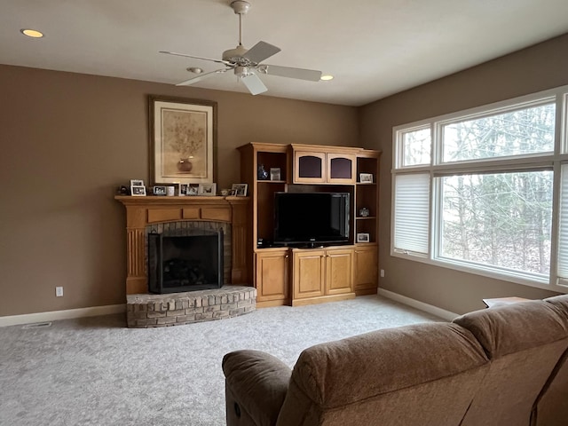 living room with ceiling fan, a fireplace, baseboards, and light colored carpet