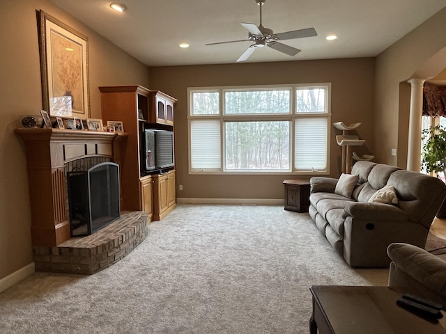 living area featuring light carpet, a fireplace, and baseboards