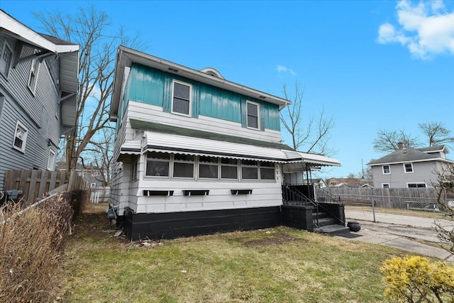 view of front facade featuring board and batten siding, a front yard, and fence