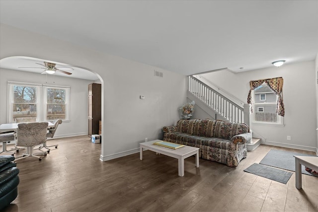 living room featuring plenty of natural light, stairs, arched walkways, and wood finished floors