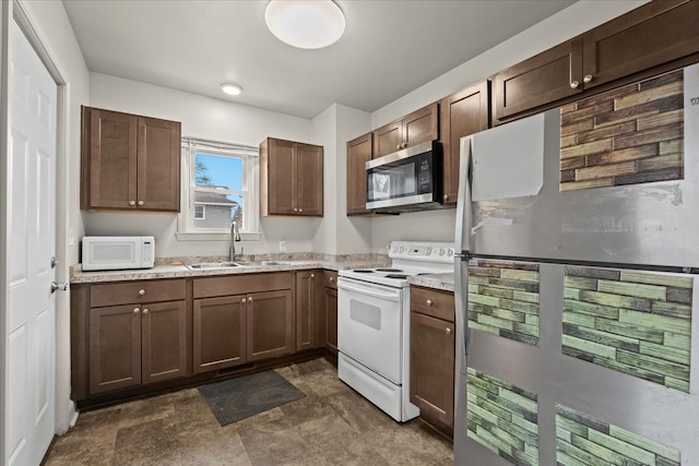 kitchen with light stone countertops, stone finish flooring, appliances with stainless steel finishes, and a sink