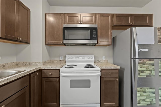 kitchen featuring stainless steel appliances, light countertops, and dark brown cabinetry