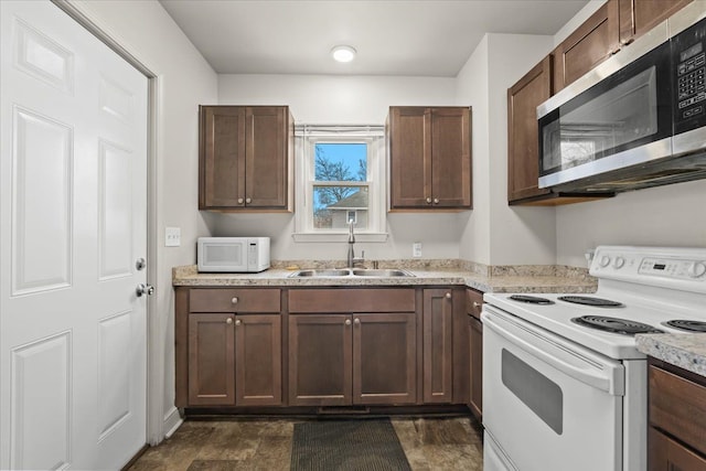 kitchen featuring light countertops, white appliances, a sink, and dark brown cabinetry