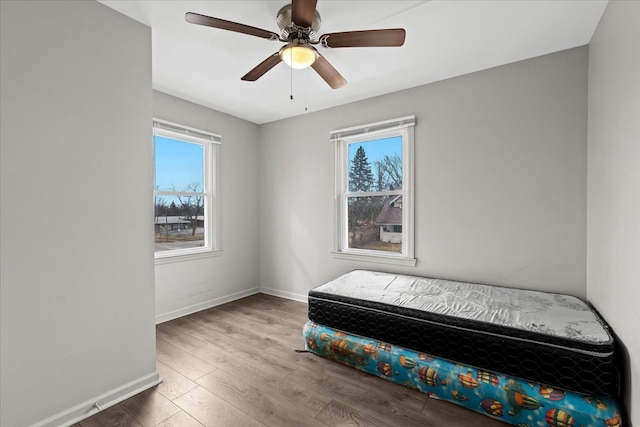 bedroom with multiple windows, baseboards, and wood finished floors