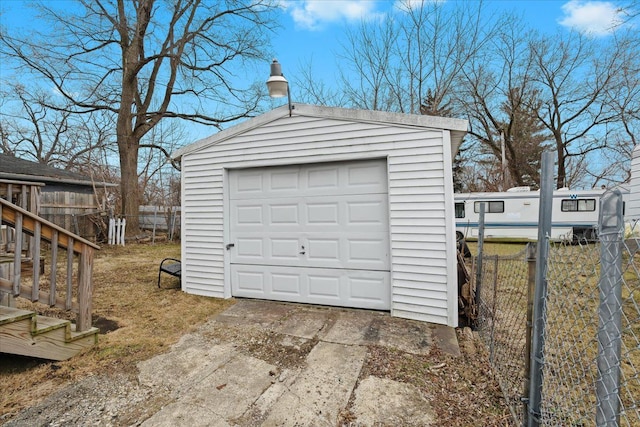 detached garage featuring driveway and fence