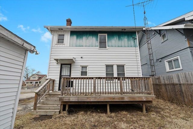 back of house with a deck, fence, a chimney, and board and batten siding