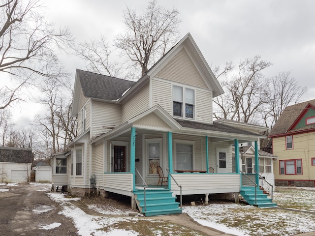 view of front of property featuring an outbuilding, a porch, and roof with shingles