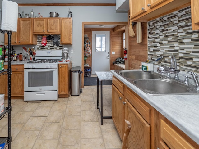 kitchen featuring backsplash, brown cabinets, a sink, and gas range gas stove