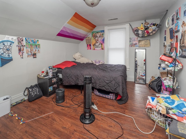 bedroom featuring lofted ceiling, visible vents, baseboards, and wood finished floors