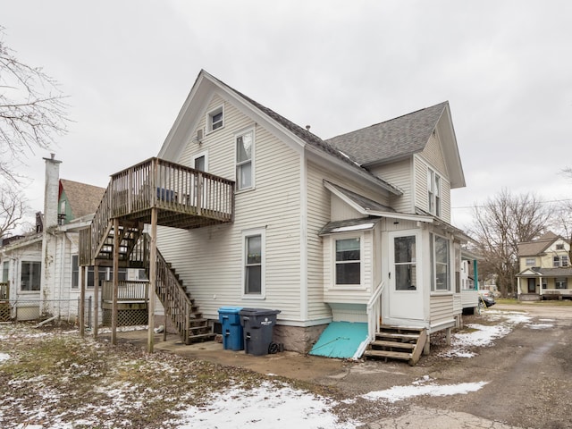 view of property exterior featuring a deck, a shingled roof, stairs, and entry steps