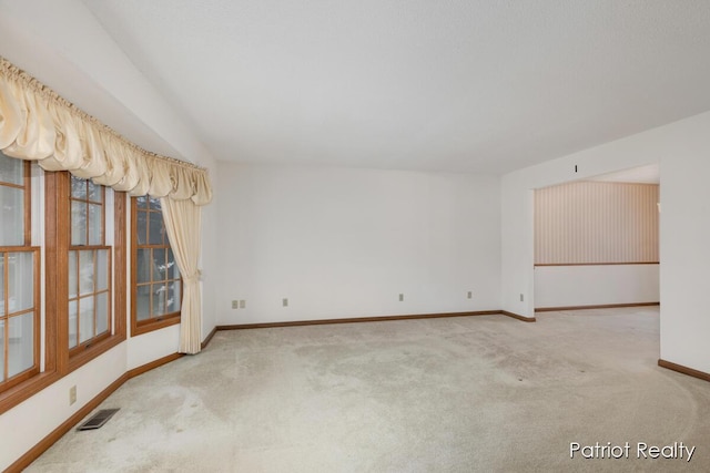 carpeted spare room with visible vents and baseboards