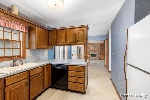 kitchen with freestanding refrigerator, a sink, dishwasher, a peninsula, and wallpapered walls