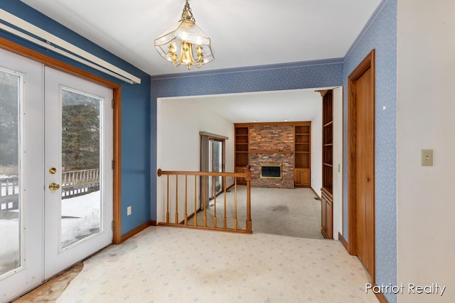 entryway with wallpapered walls, carpet, french doors, a fireplace, and a notable chandelier