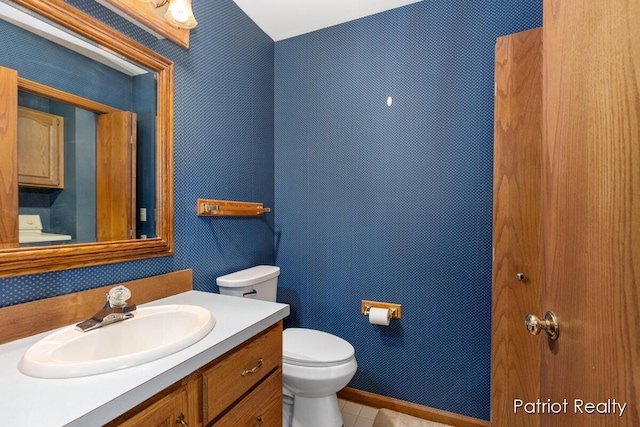 half bathroom featuring tile patterned floors, vanity, toilet, and wallpapered walls