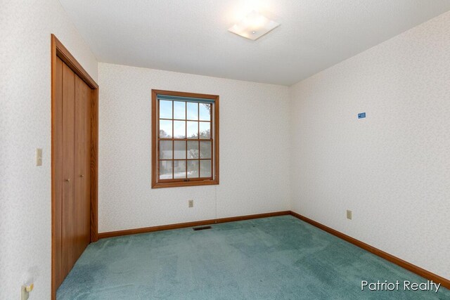 carpeted spare room featuring baseboards, visible vents, and wallpapered walls