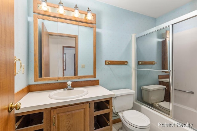 full bathroom featuring enclosed tub / shower combo, vanity, toilet, and wallpapered walls