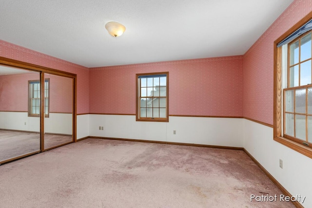 unfurnished room featuring baseboards, carpet, and wallpapered walls