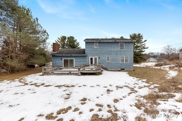 snow covered house with a deck and a chimney