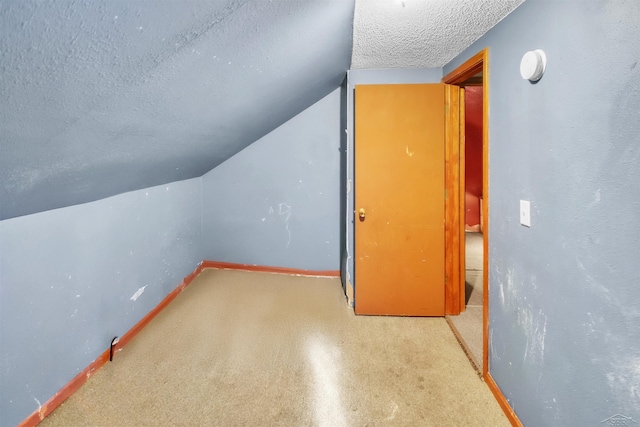 bonus room featuring lofted ceiling, a textured ceiling, and baseboards