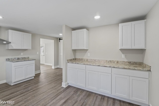 kitchen with a barn door, white cabinets, dark wood-style flooring, and recessed lighting