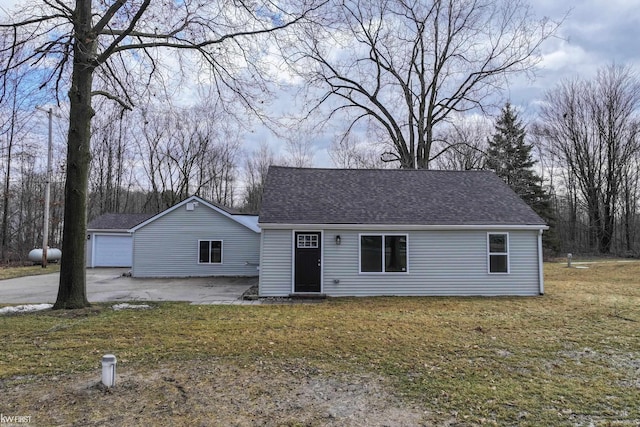 view of front facade featuring a shingled roof, a front yard, and a garage