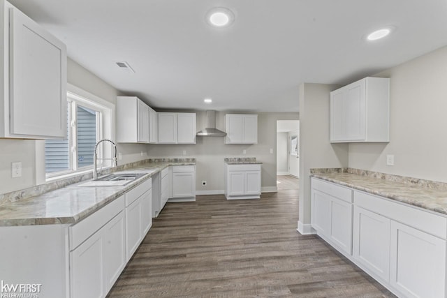 kitchen featuring dark wood-style flooring, visible vents, white cabinets, a sink, and wall chimney exhaust hood