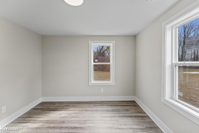 spare room featuring baseboards and wood finished floors