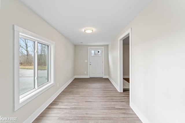 doorway to outside with light wood finished floors, a wealth of natural light, and baseboards