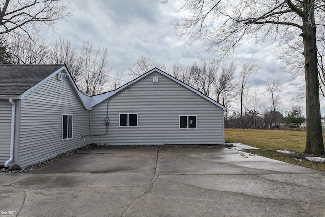 view of property exterior with a yard, roof with shingles, and driveway