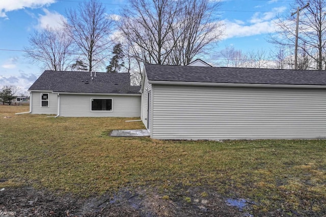 rear view of property with roof with shingles and a lawn