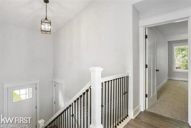 hall with baseboards, wood finished floors, and an upstairs landing