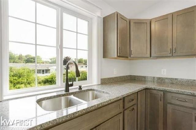 kitchen with light stone counters and a sink