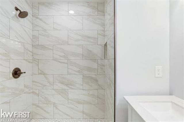 bathroom featuring a tile shower and vanity