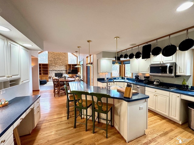 kitchen featuring dark countertops, light wood-style flooring, appliances with stainless steel finishes, open floor plan, and a fireplace