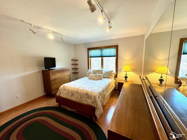 bedroom with a textured ceiling, wood finished floors, and baseboards