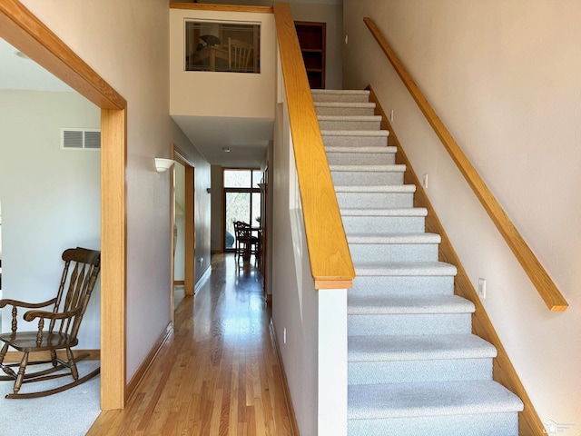 stairway featuring baseboards, visible vents, and wood finished floors