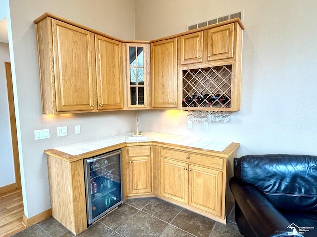 bar with visible vents, a sink, wet bar, beverage cooler, and baseboards