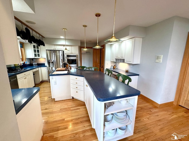 kitchen featuring appliances with stainless steel finishes, dark countertops, light wood-style flooring, and white cabinets