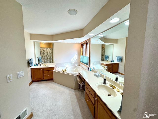 bathroom featuring a garden tub, visible vents, two vanities, and a sink