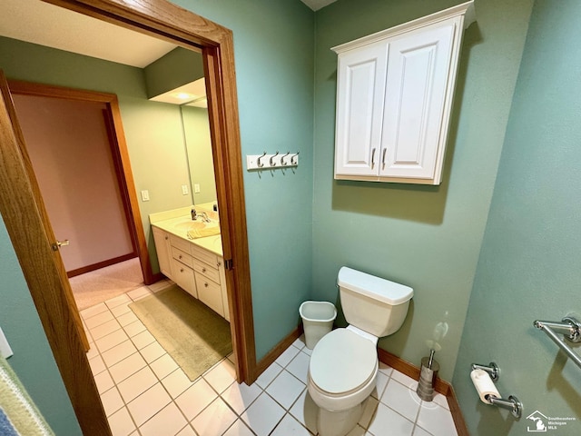 half bathroom featuring tile patterned flooring, vanity, toilet, and baseboards