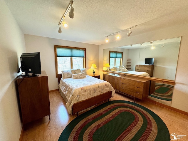 bedroom featuring a textured ceiling, light wood-style flooring, and baseboards